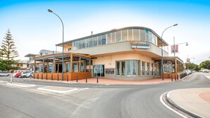 Un hotel moderno con fachada curva, grandes ventanales y una zona de estar exterior cubierta.