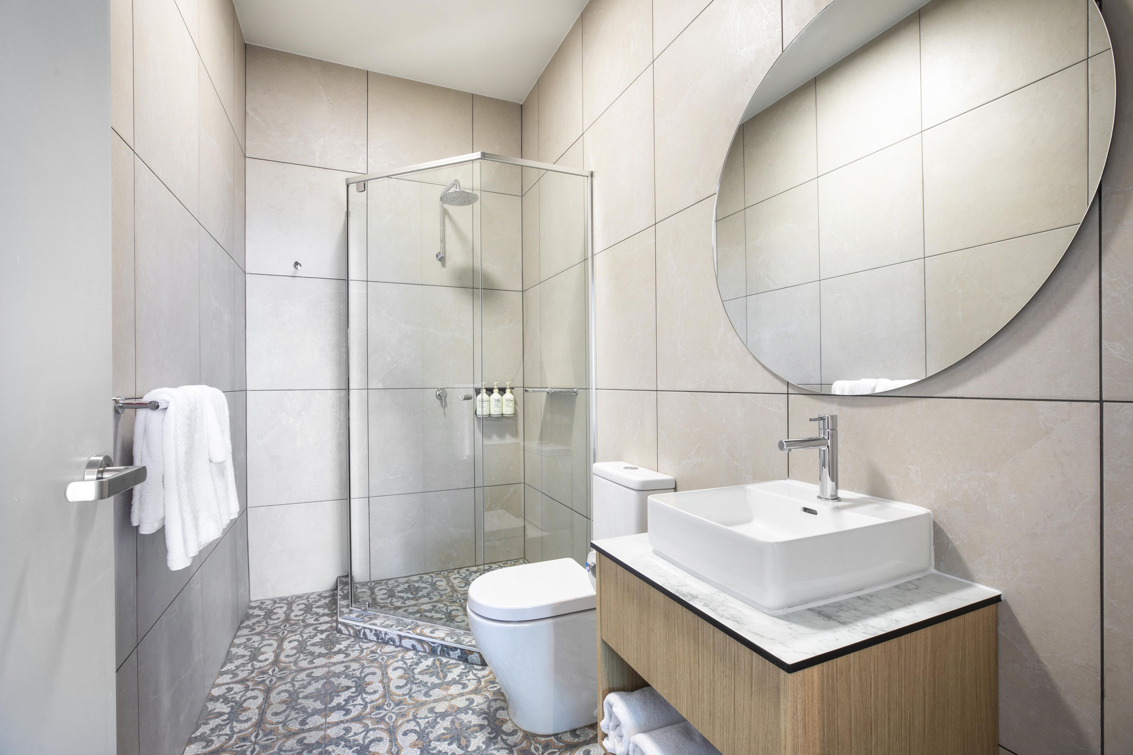 A modern bathroom with a glass-enclosed shower, a white toilet, and a vanity with a sink.