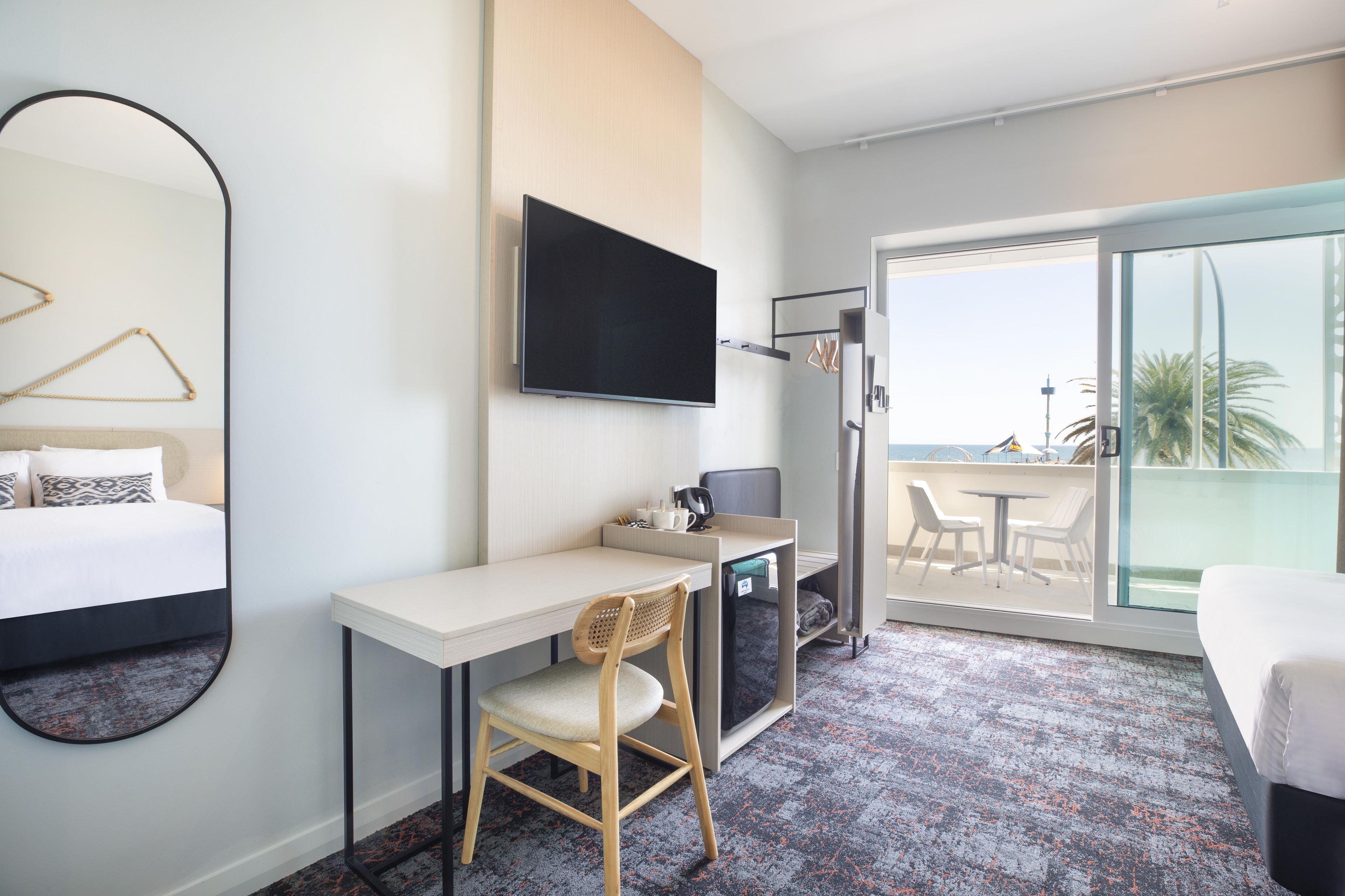 Habitació d'hotel amb llit, escriptori, cadira, televisió i balcó amb vistes.