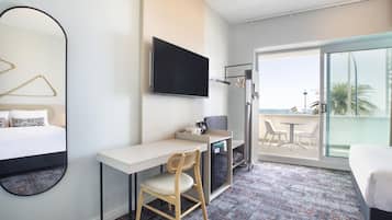 Habitació d'hotel amb llit, escriptori, cadira, televisió i balcó amb vistes.