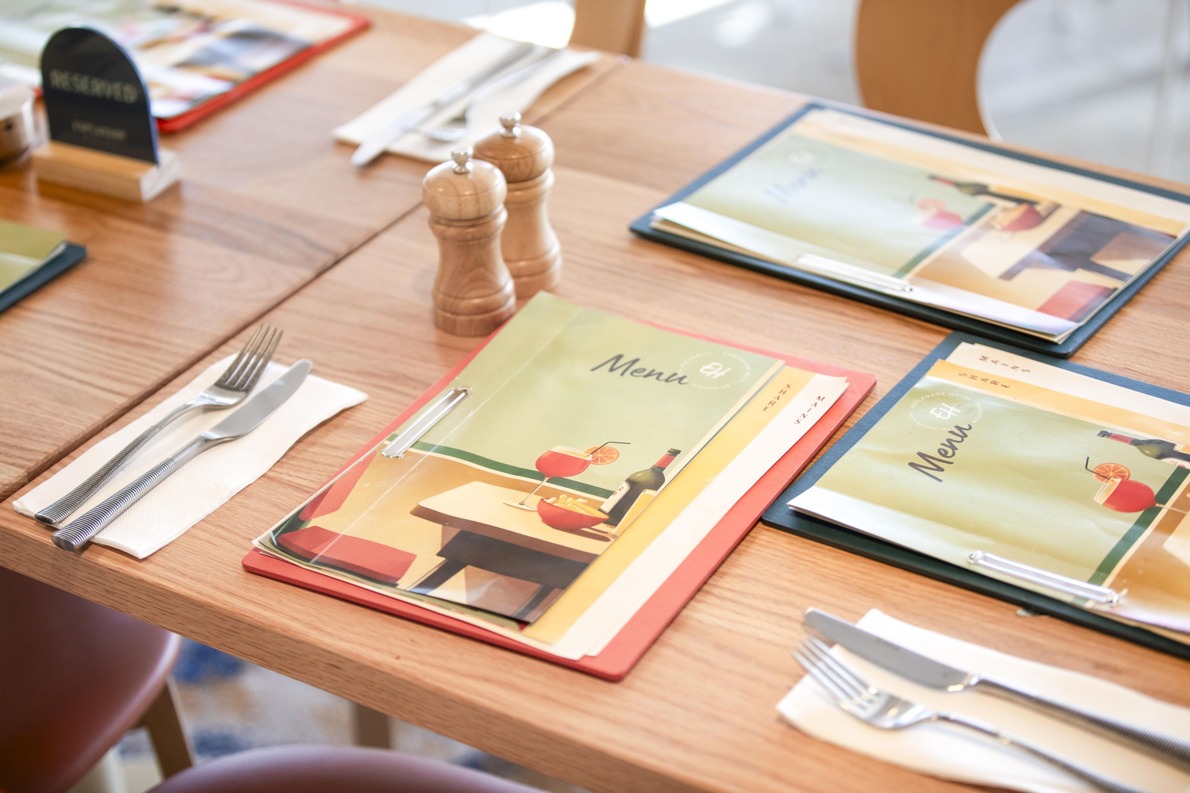 A table set with a menu, cutlery, and a salt and pepper shaker.