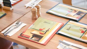 A table set with a menu, cutlery, and a salt and pepper shaker.
