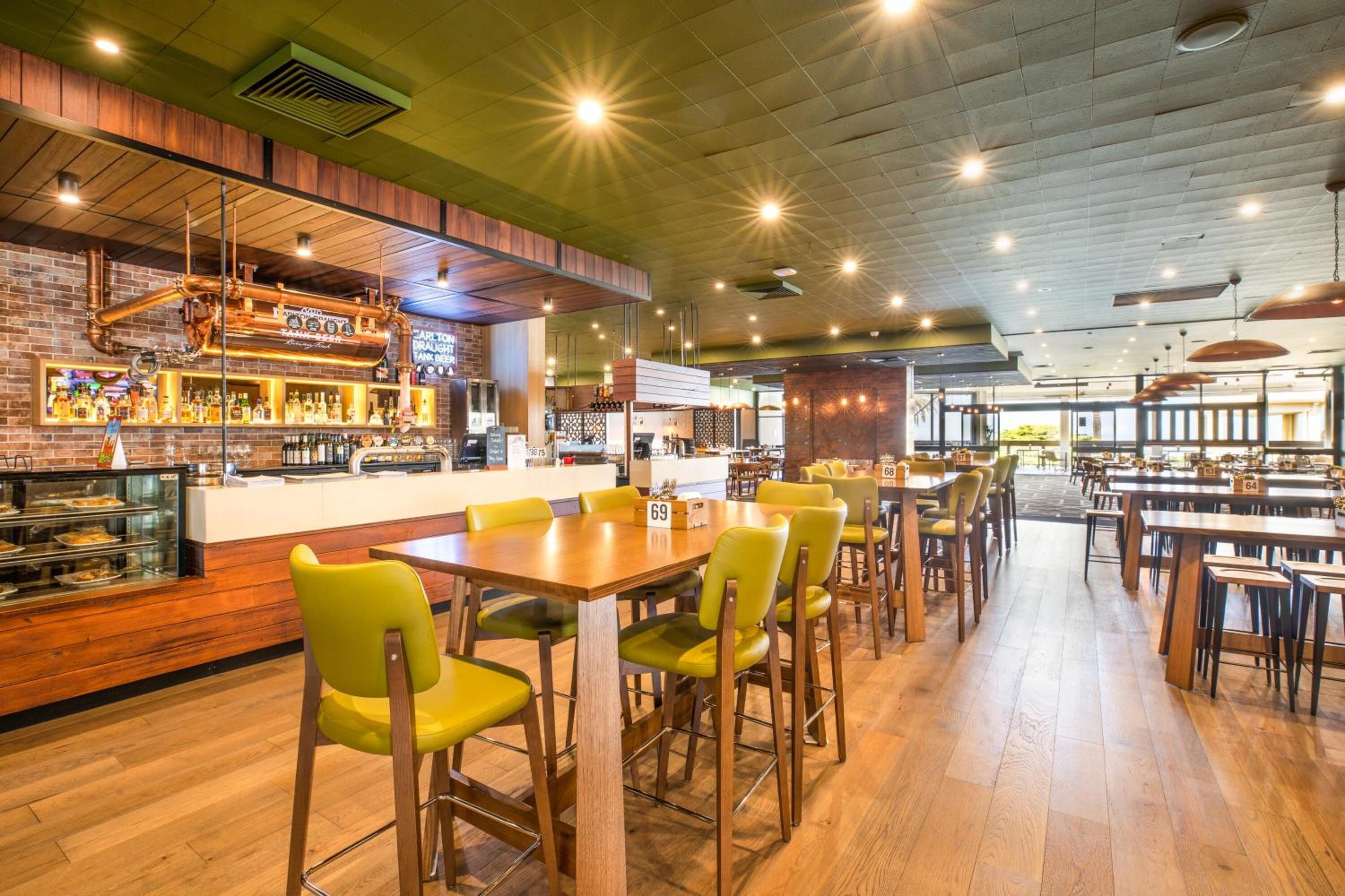 Un interior de restaurante con barra, mesas y sillas de madera, y pared de ladrillo.