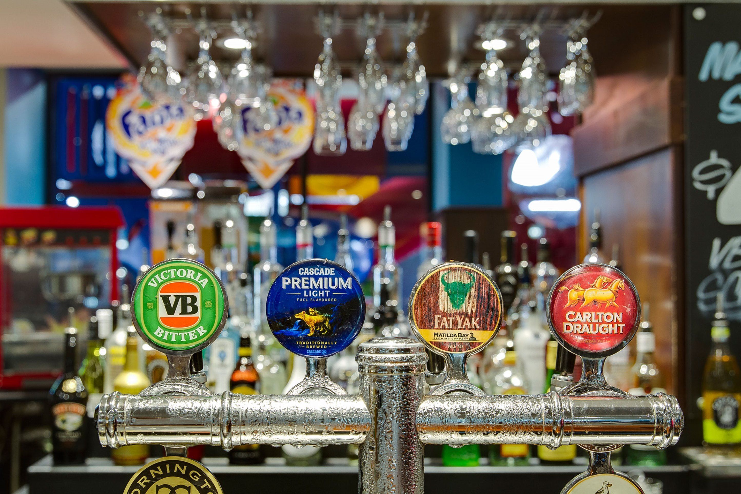 A bar with multiple beer taps, including brands like Victoria Bitter, Cascade Premium Light, Fat Yak, and Carlton Draught.