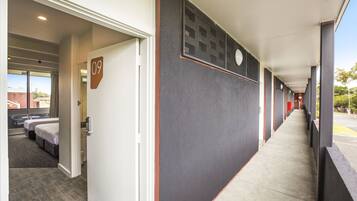 A hotel corridor with a number '09' sign, a bed, and a window with a view of the outside.