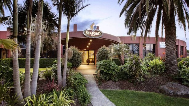 The exterior of the Seaford Hotel with a well-maintained garden and palm trees.