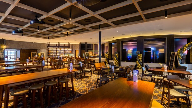 Un amplio hall de hotel con varias zonas de estar, un bar y vistas de la ciudad a través de grandes ventanales.