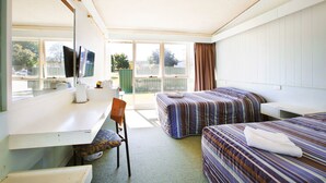 Habitación de hotel con escritorio, dos camas, una silla y televisor.