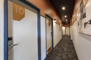 A hallway with doors marked with numbers, carpeted flooring, and recessed lighting.
