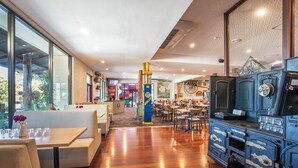 Un restaurant avec un plancher en bois, des banquettes et un vieux poêle bleu d’époque.