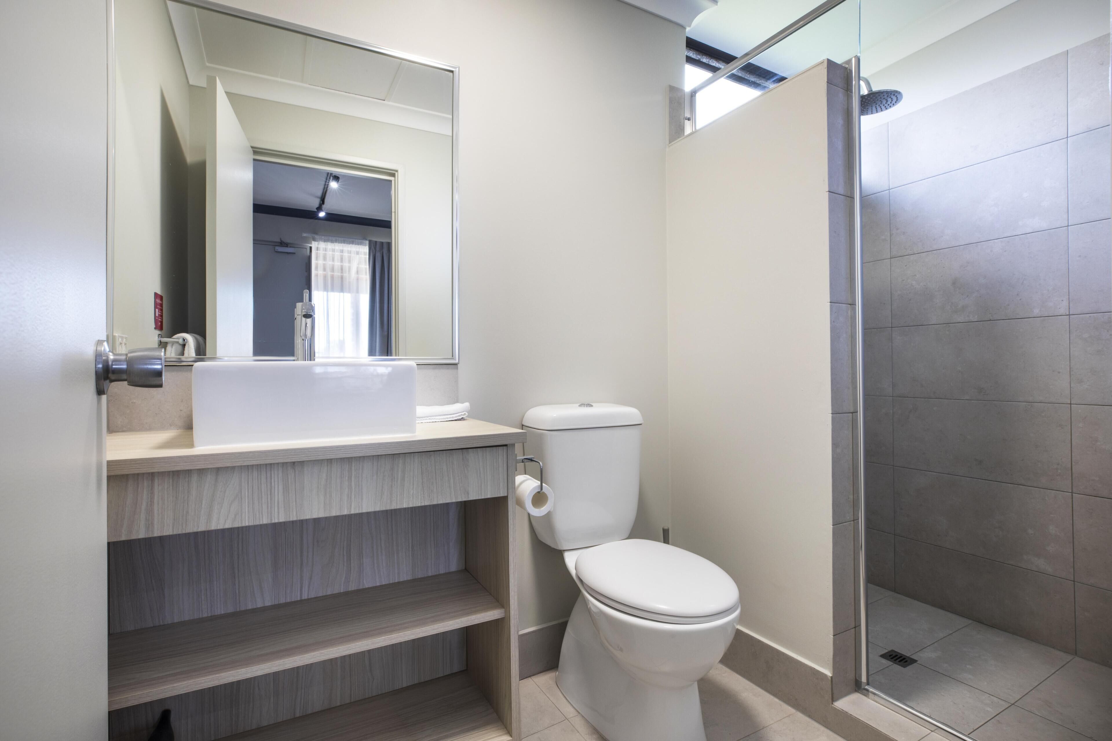 A modern bathroom with a toilet, a sink, and a shower.