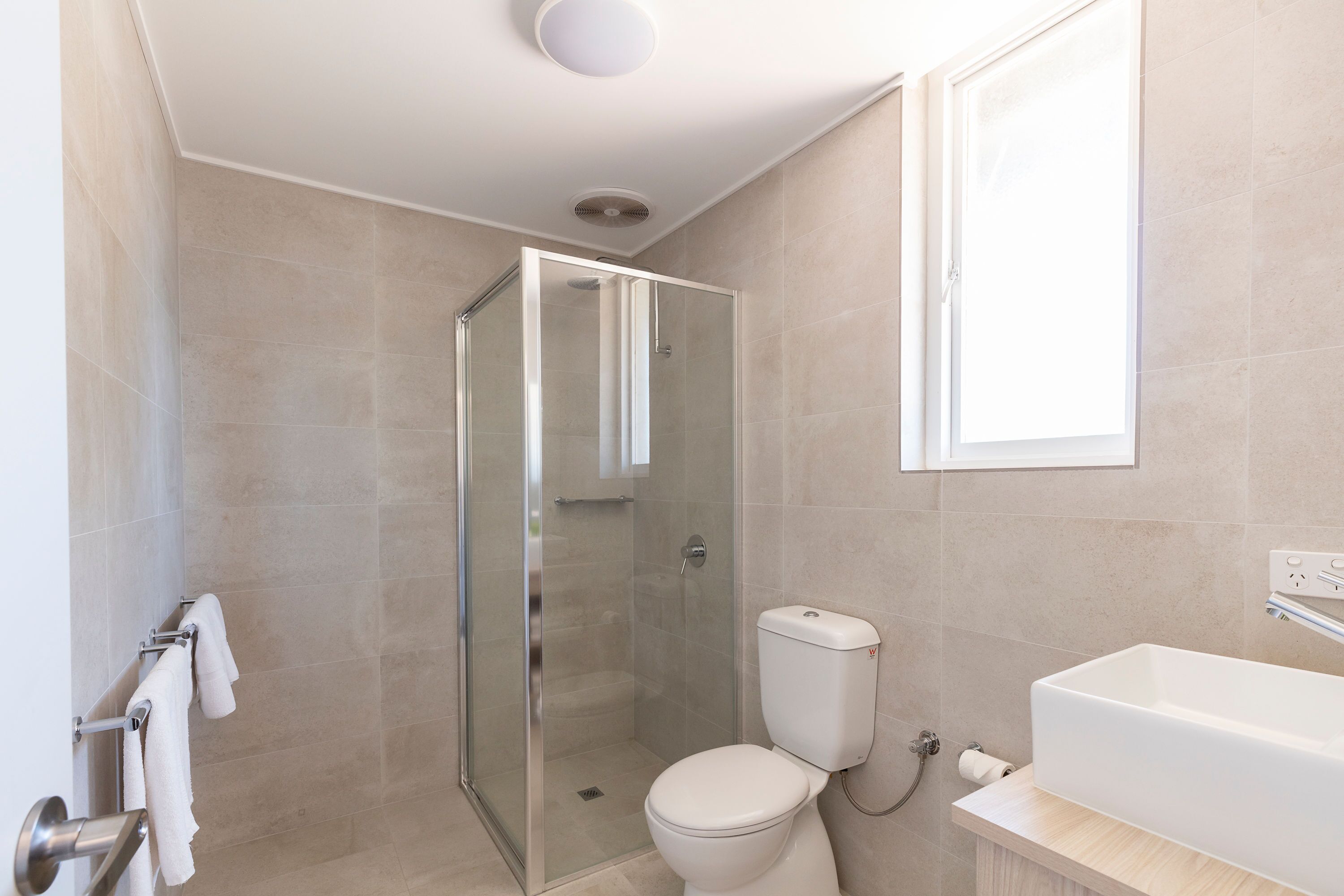 Un baño moderno con cabina de ducha de vidrio, inodoro blanco y bañera grande.