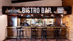 Een bistrobar met een bordje waarop staat dat het deel uitmaakt van Hotel & Motel Wintersun. Er staan drie krukken voor de bar.