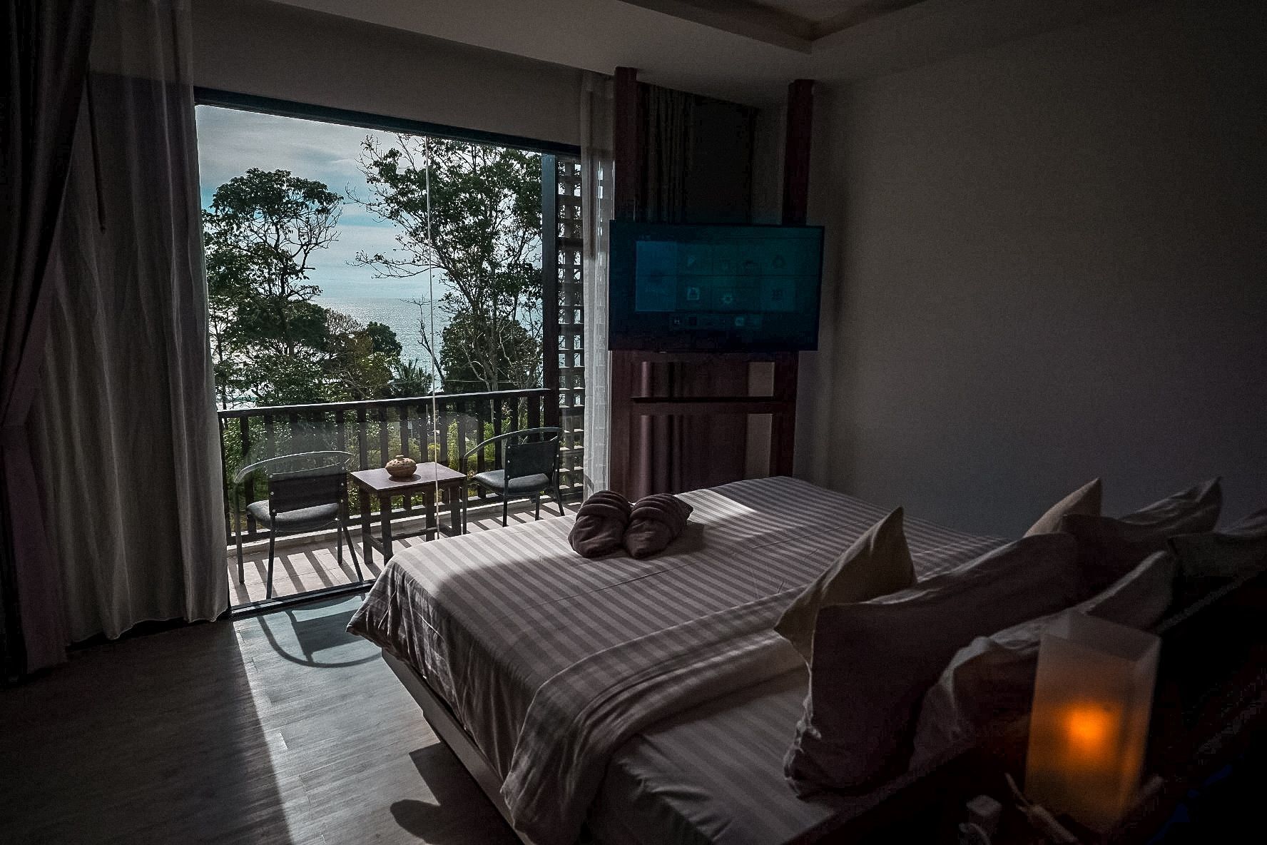 Un dormitorio con una cama grande, televisión y balcón con mesa y sillas.