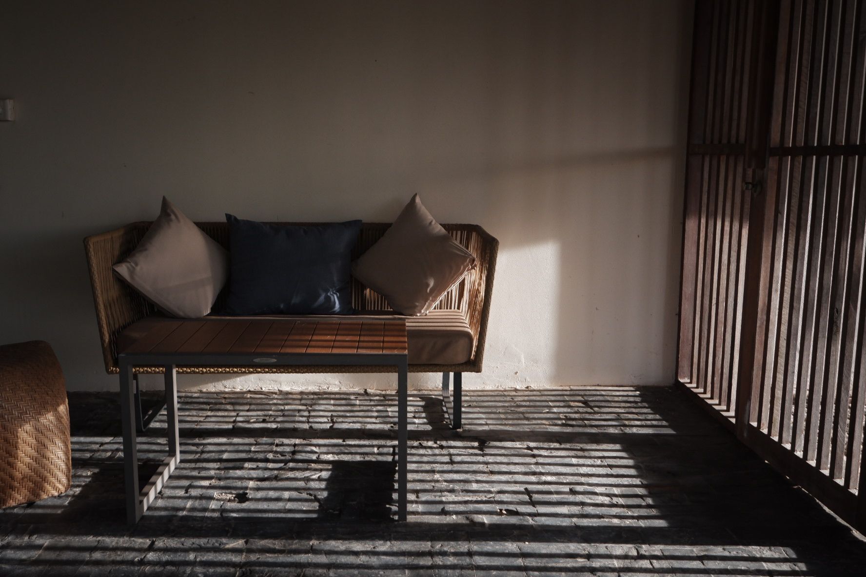 Un sofá de madera con cojines en una habitación con suelo de metal corrugado y baranda de madera.