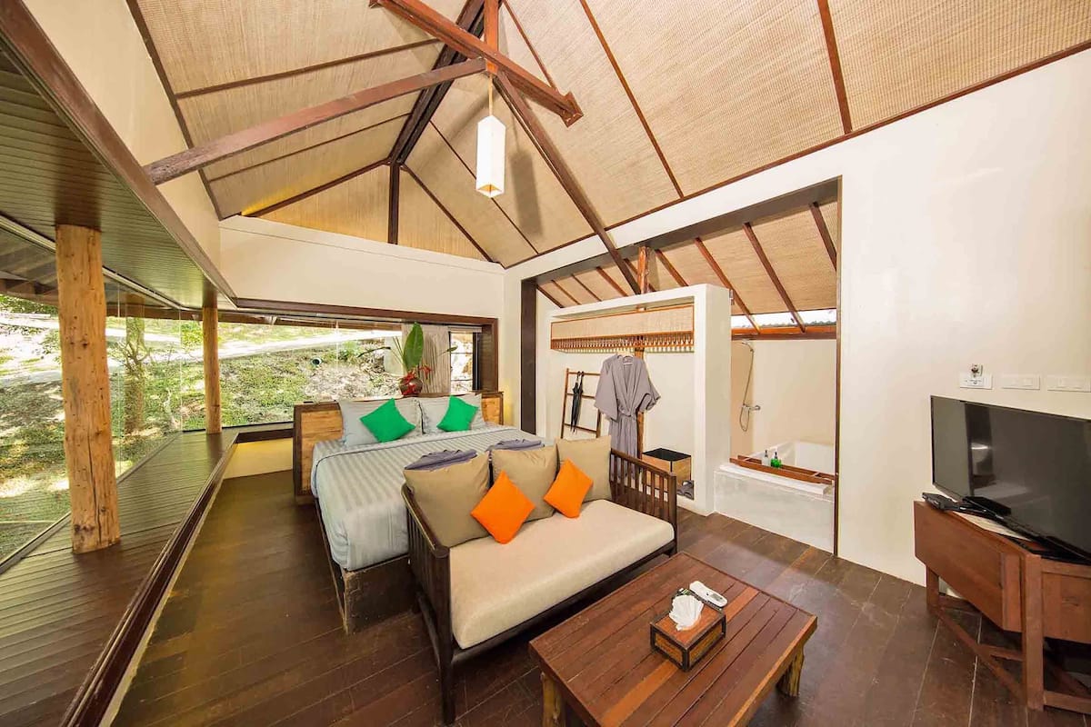 A spacious room with a large bed, a sofa, a television, and a wooden coffee table.