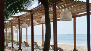 Un padiglione sulla spiaggia con travi di legno e lanterne bianche, con vista sul mare.