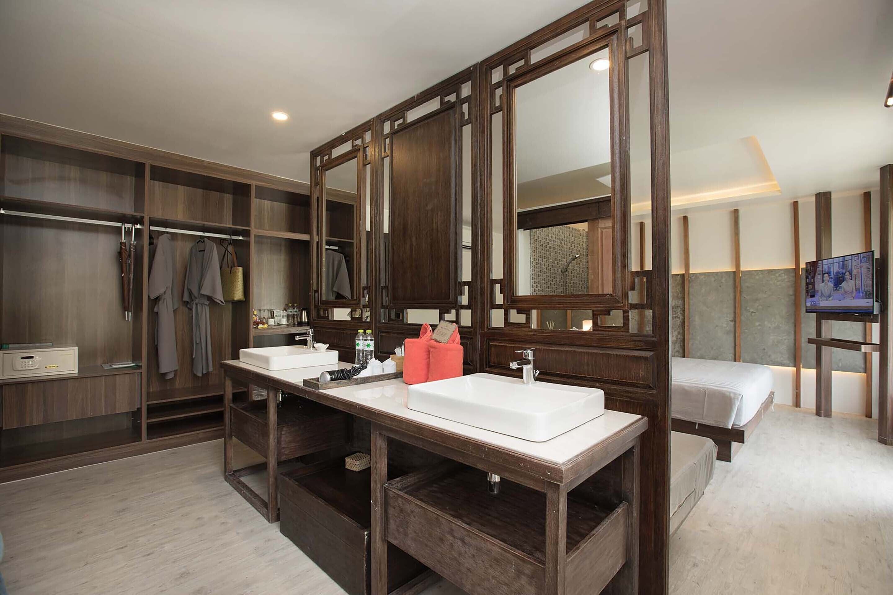 Un baño de hotel moderno con un espejo grande, dos lavamanos, un tocador y un vestidor.