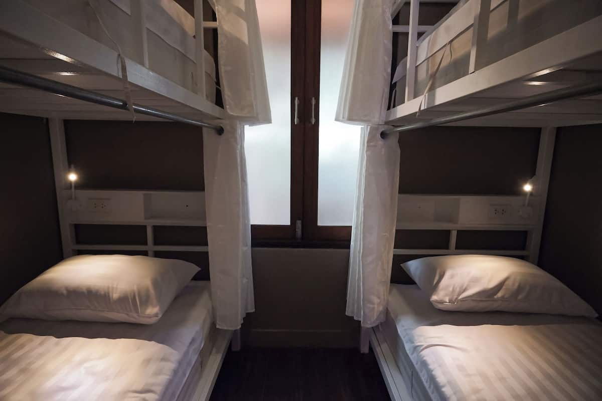 A room with two bunk beds, each with a pillow and a headboard.