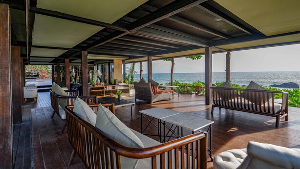 Un patio esterno con mobili in legno, un tavolo e vista sul mare.