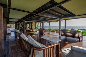 Une terrasse extérieure avec des meubles en bois, une table et une vue sur la mer.
