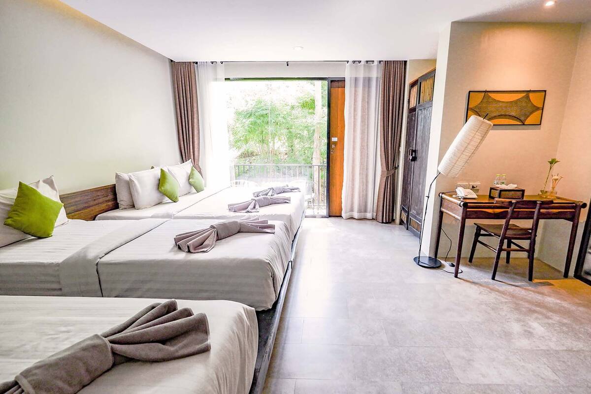 A hotel room with two beds, a desk with a chair, a telephone, and a window with curtains.