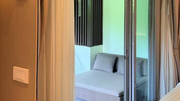 A hotel room with a bed, a table, a chair, and a view through a glass door.