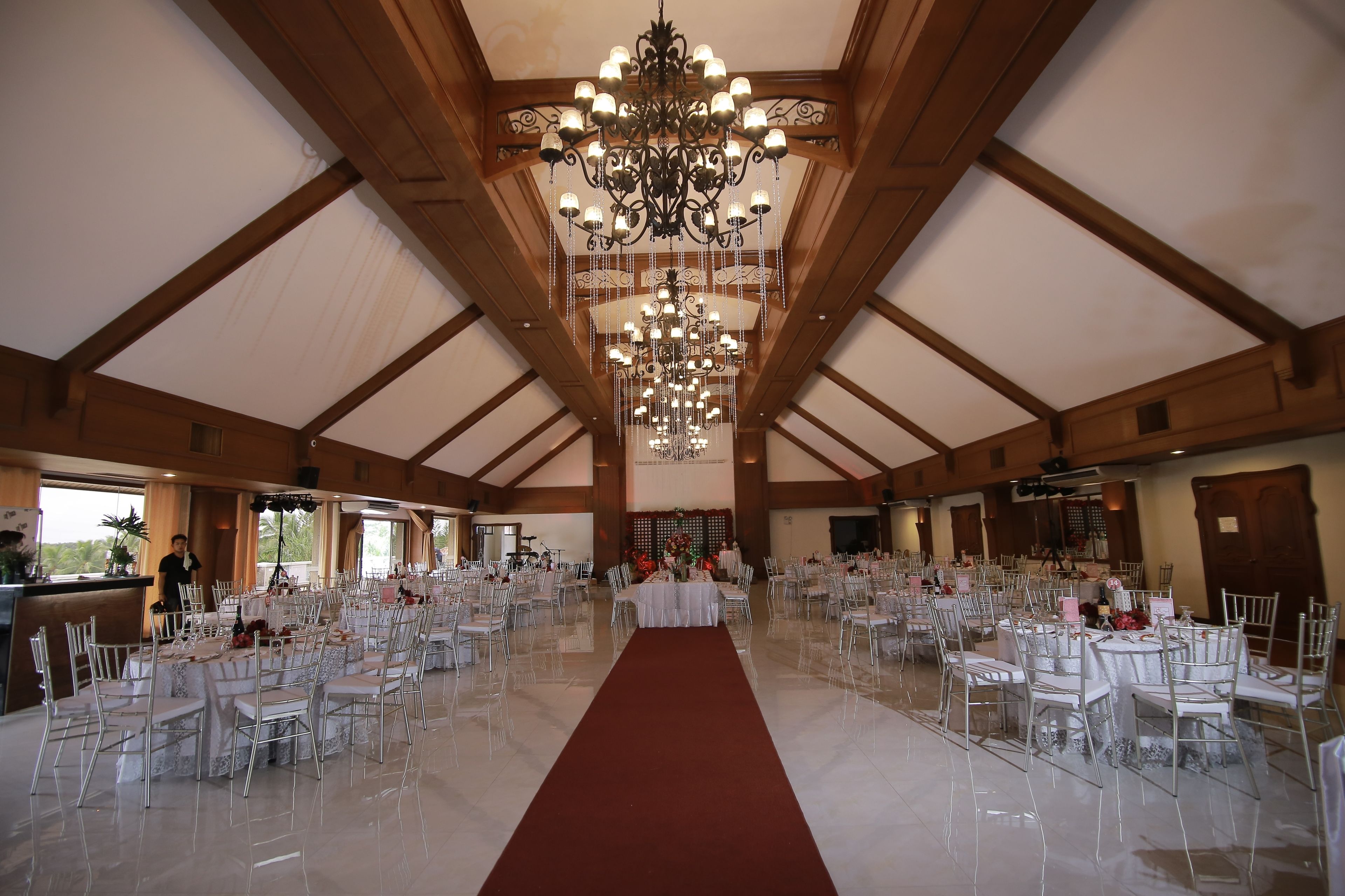 A large hall with a high ceiling, chandeliers, and rows of tables and chairs.