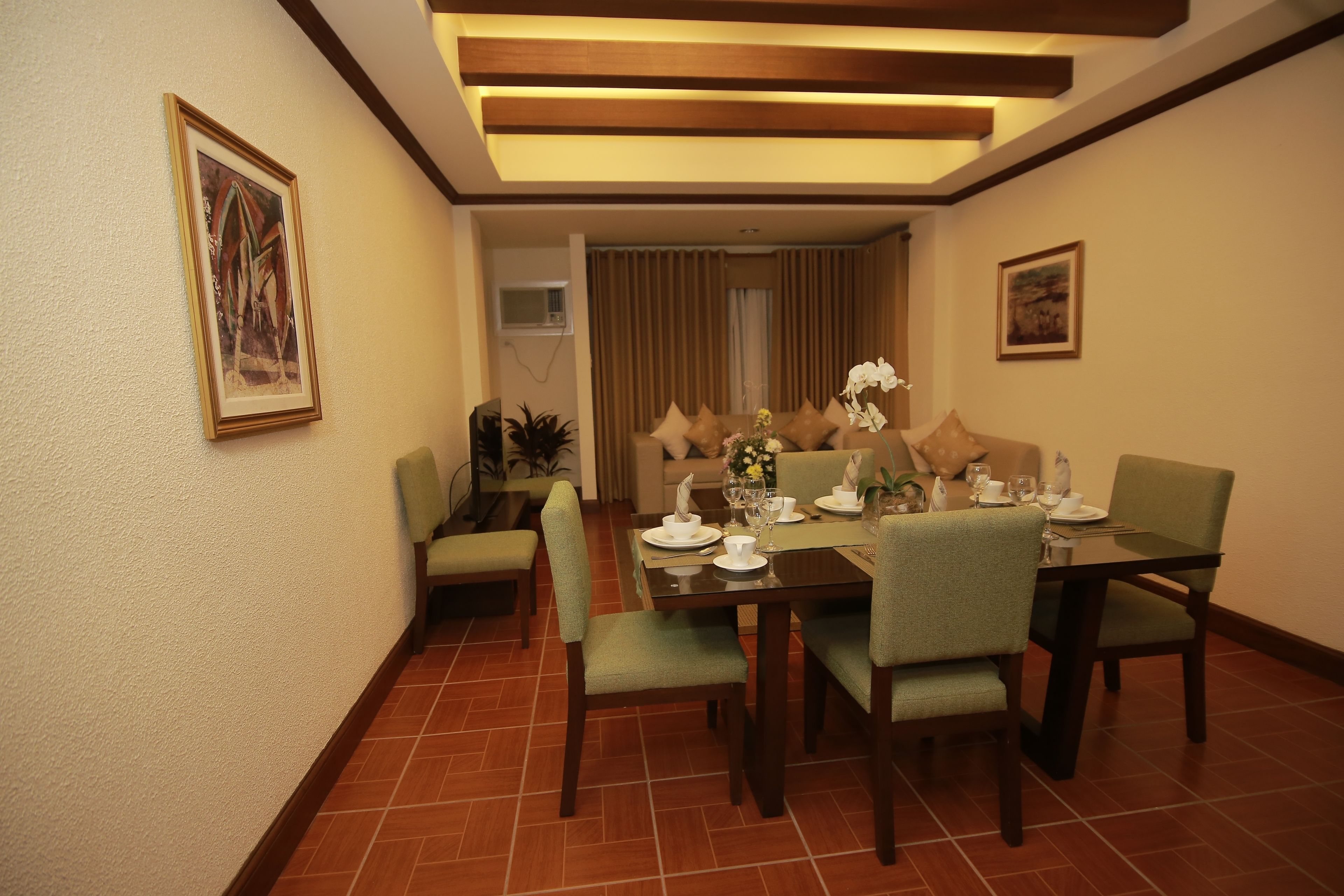 A dining area with a table set for four, chairs, a ceiling light fixture, and a framed picture on the wall.