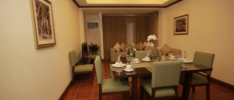 A dining area with a table set for four, chairs, a ceiling light fixture, and a framed picture on the wall.