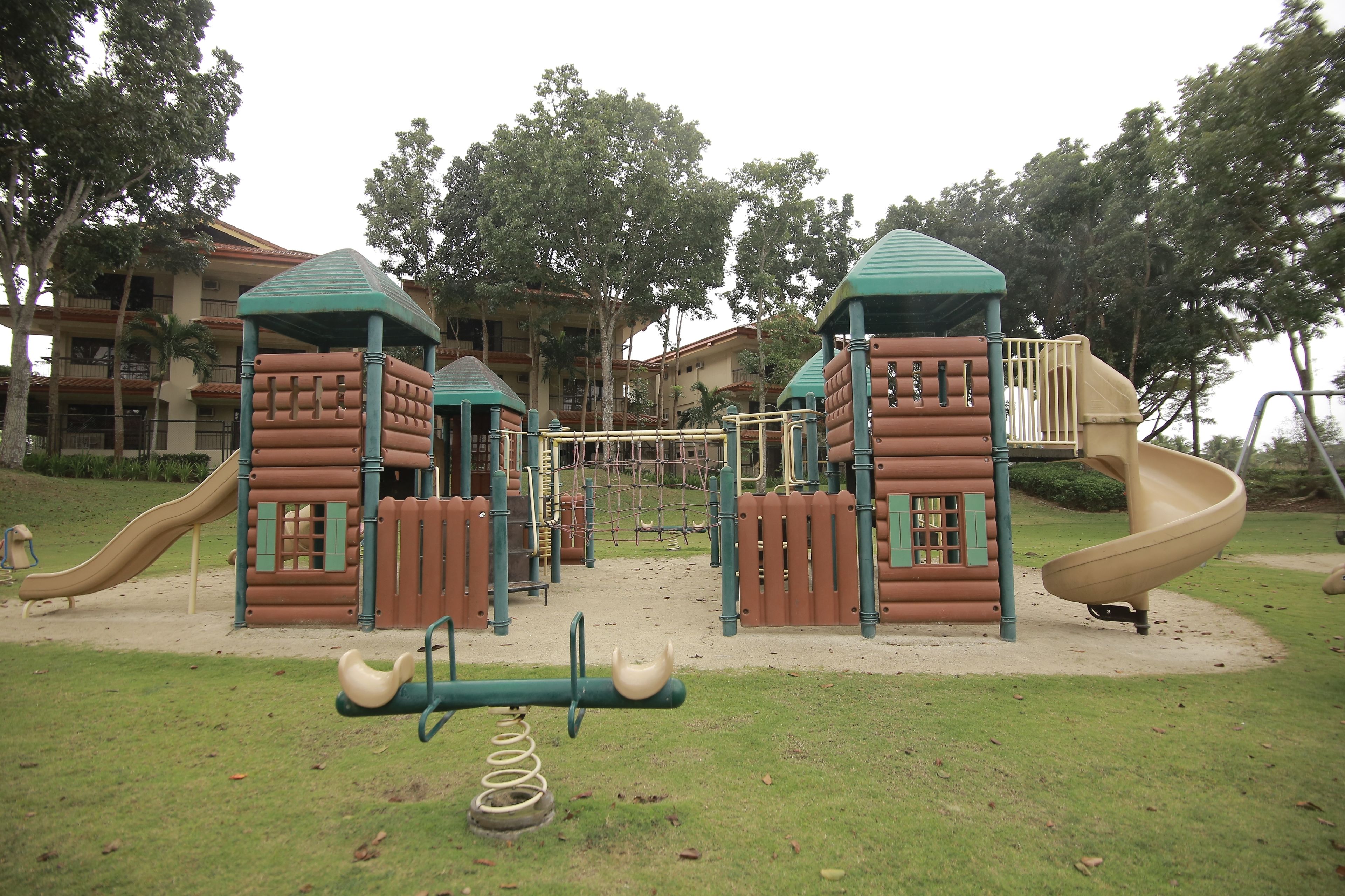 A playground with a slide, climbing structures, and a seesaw.