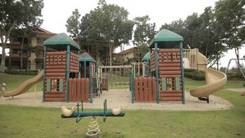 A playground with a slide, climbing structures, and a seesaw.