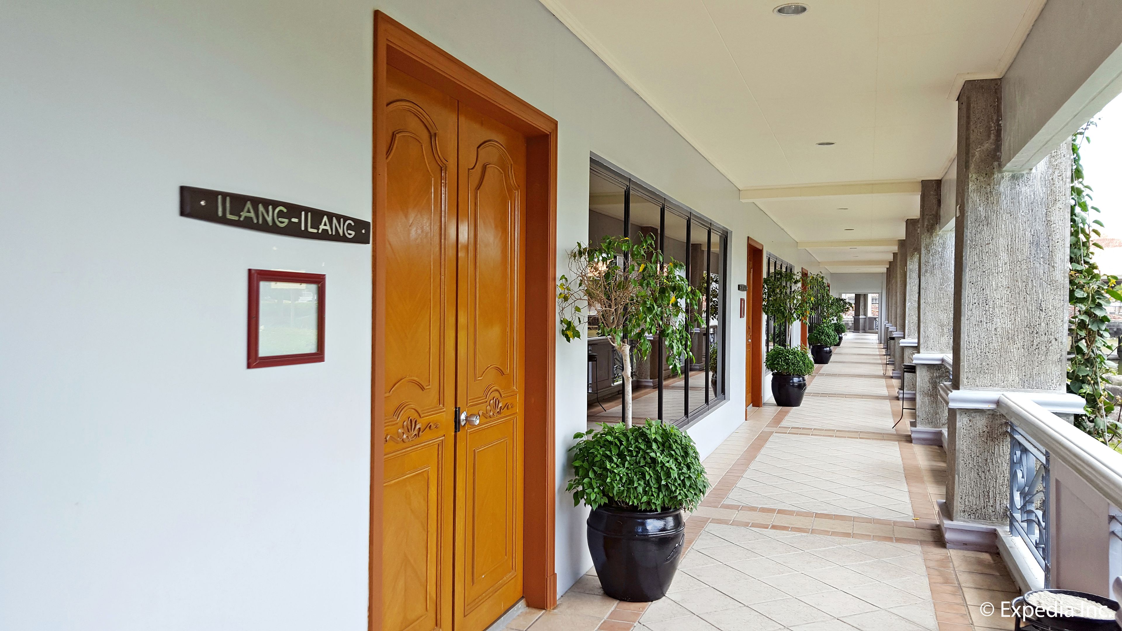 A corridor with wooden doors, potted plants, and a sign reading "LANG-ILANG".