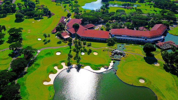 An aerial view of a golf course with a clubhouse, water features, and surrounding greenery. - The Suites at Mount Malarayat (Lipa)