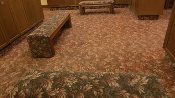 A room with a patterned carpet, wooden cabinets, and a bench.
