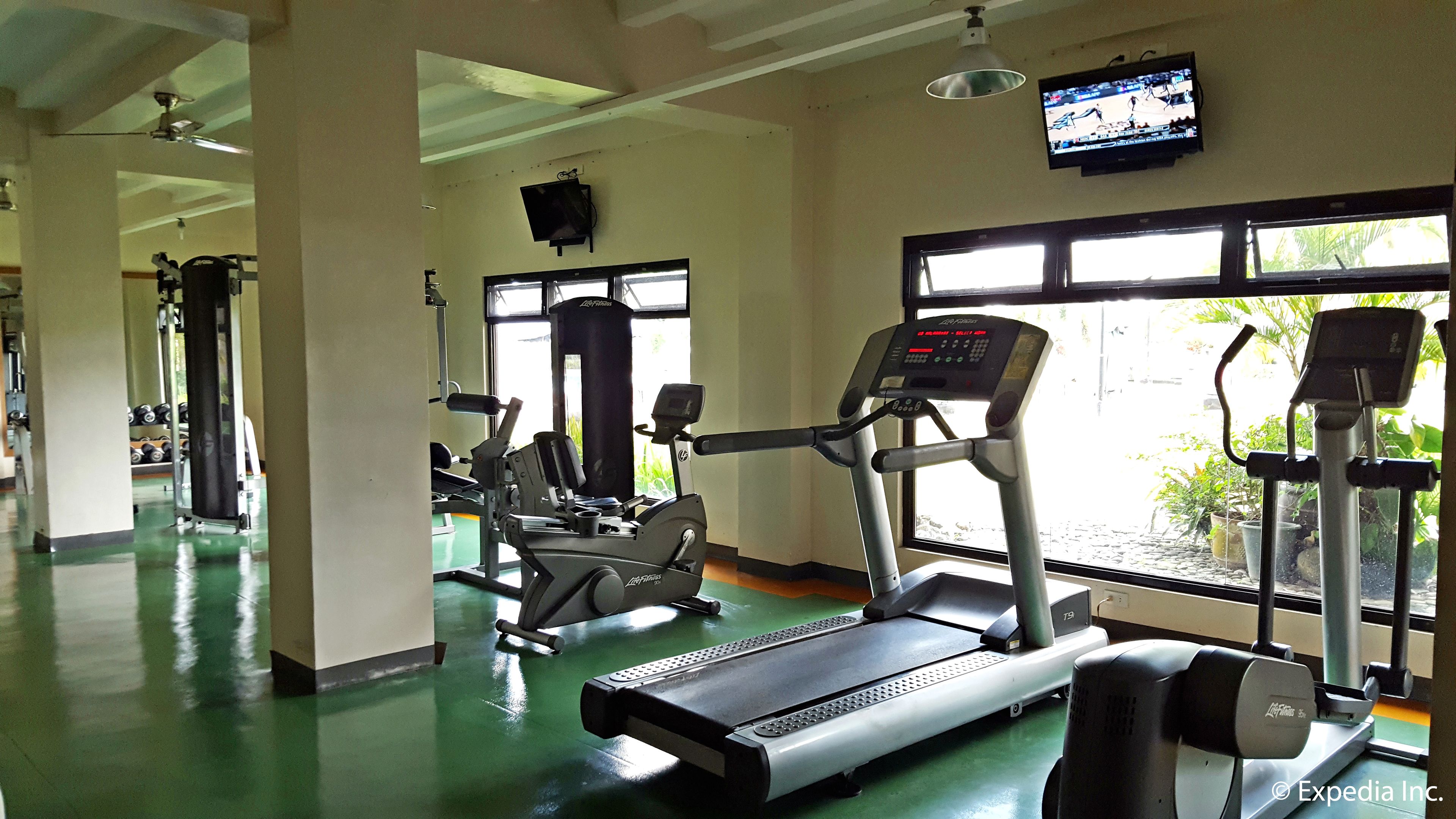 A gym with treadmills, weight machines, and a TV on the wall.