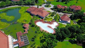 Ett flygbildsbild av ett semesterområde med en swimmingpool, en golfbana och flera byggnader med röda tak.