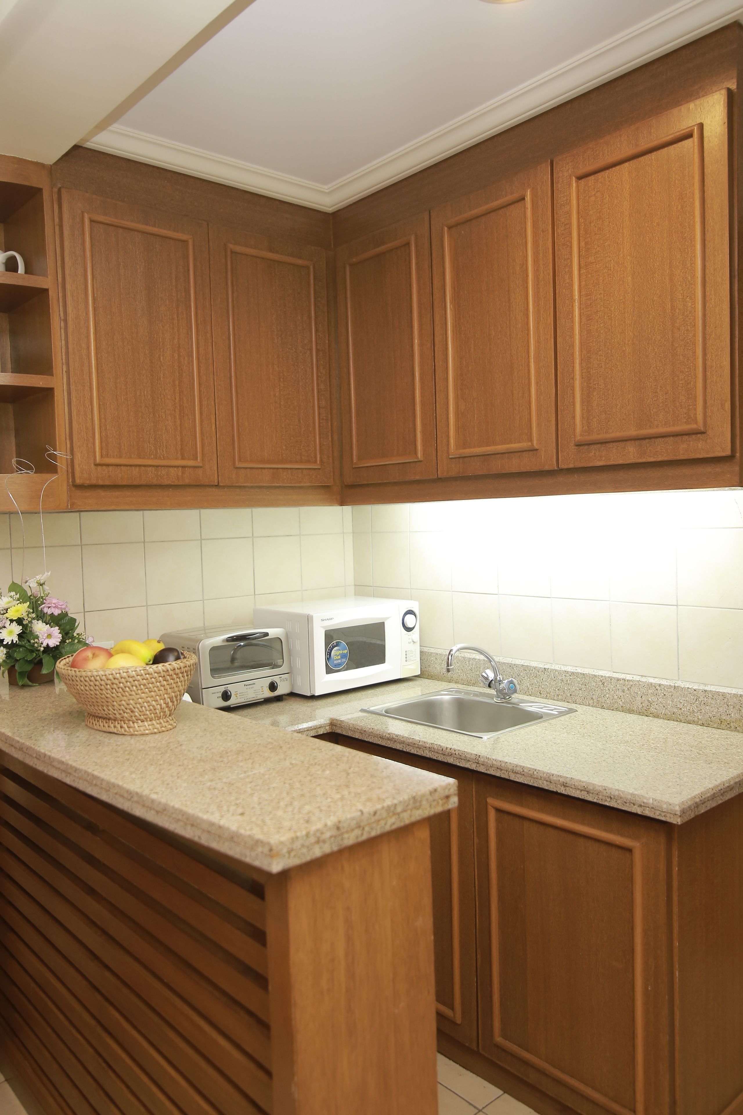 A kitchen with wooden cabinets, a microwave, a toaster, and a sink.