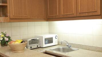 A kitchen with wooden cabinets, a microwave, a toaster, and a sink.