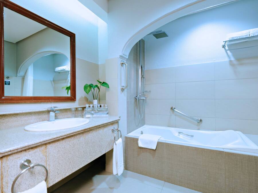 A modern bathroom with a double sink vanity, a large mirror, a bathtub, and a shower.
