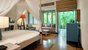 Un dormitorio con cama a dosel, un sofá, un escritorio y vistas a zonas verdes.