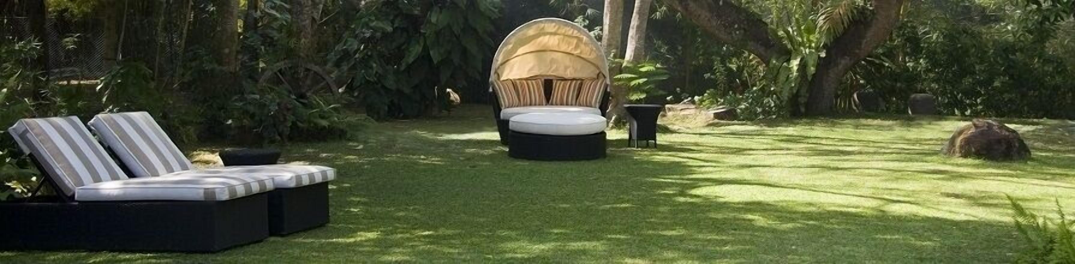 Un jardín con un sofá exterior negro, una zona de estar cubierta y una pequeña mesa.