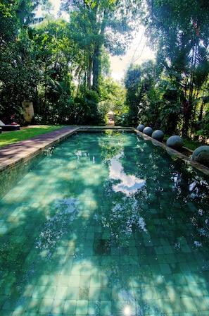 Una piscina al aire libre, sombrillas, sillones reclinables de piscina