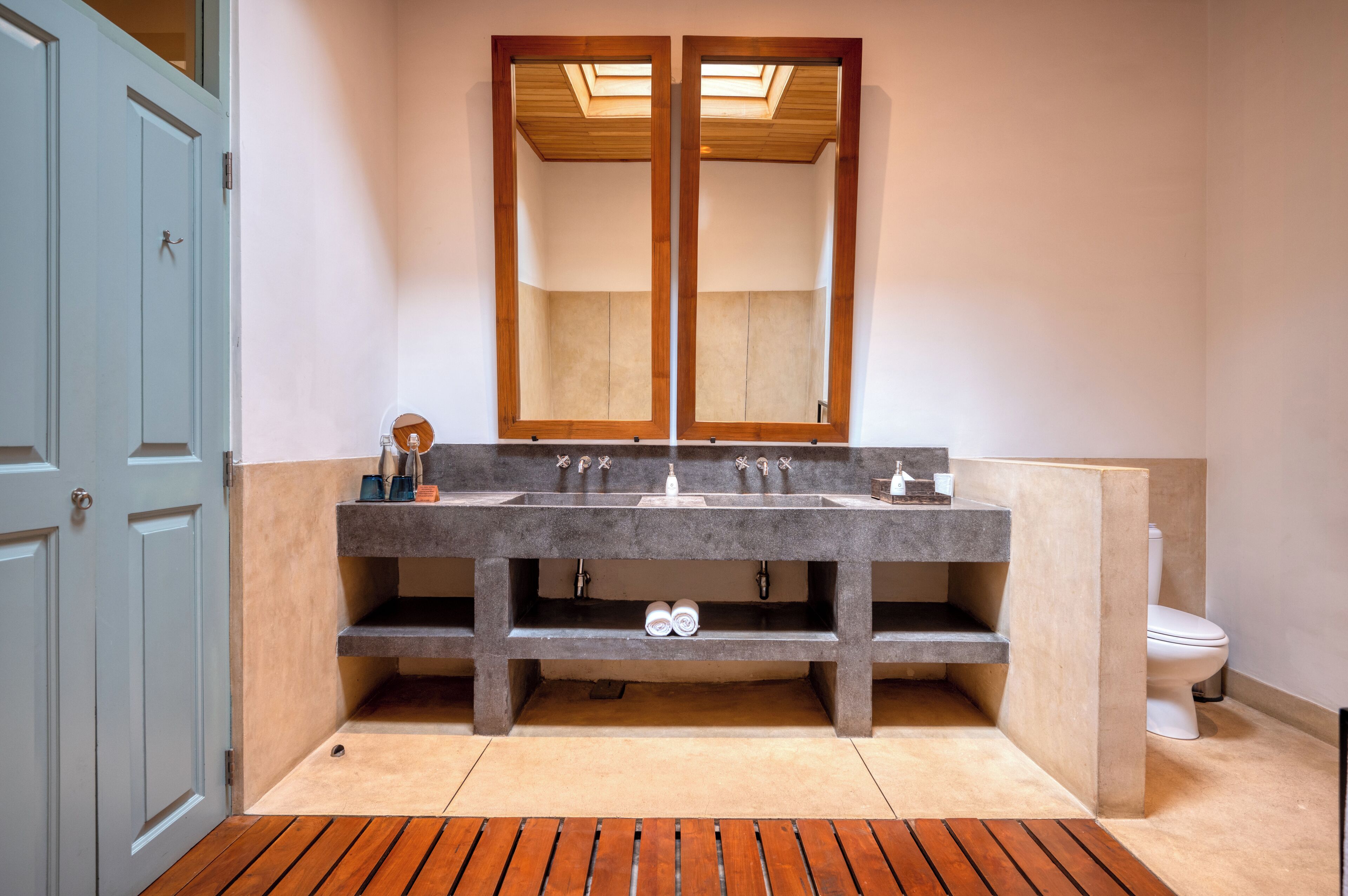A bathroom with a double sink, a toilet, and a large mirror.
