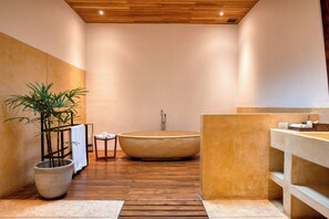A modern bathroom with a large bathtub, a potted plant, and a wooden floor. - Wallawwa (Kotugoda)