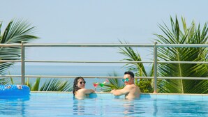 A couple in a pool with a view of the sea.