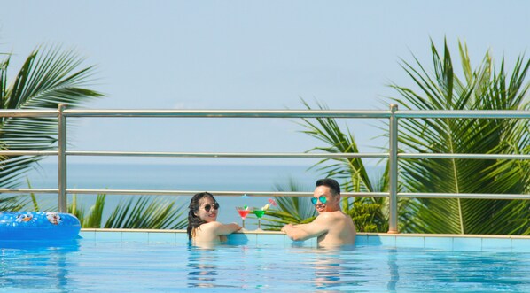A couple in a pool with a view of the sea.