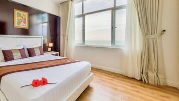 A hotel room with a large bed, a nightstand, a bedside table with a lamp, a window with curtains, and a painting on the wall.