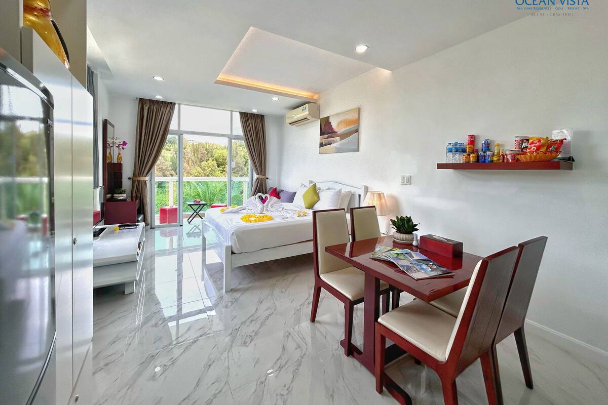 Una habitación de hotel moderna con balcón, zona de comedor y cama.