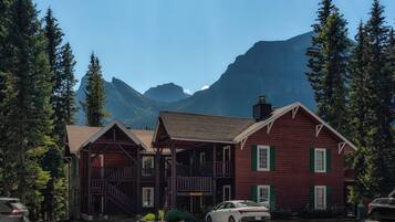 A rustic log cabin with a porch and a car parked in front.